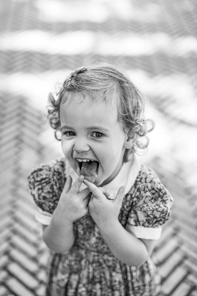 Family Session, black and white photo of a cute little girl in a beautiful dress with tongue sticking out